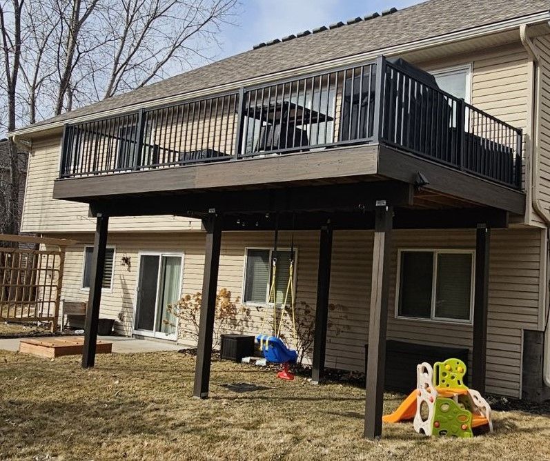 There is a large deck in the backyard of a house.