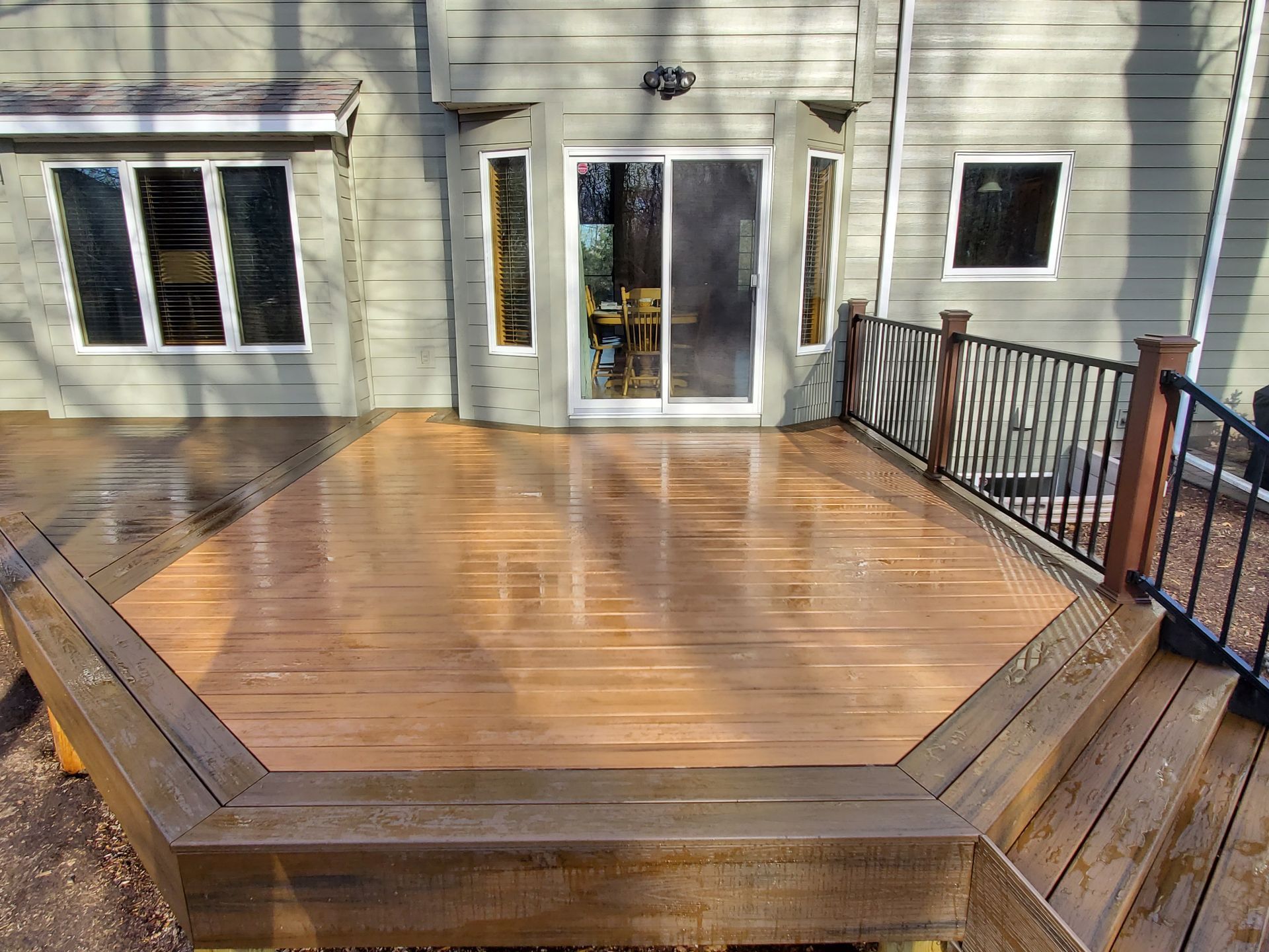 A wooden deck with a sliding glass door in the backyard of a house.