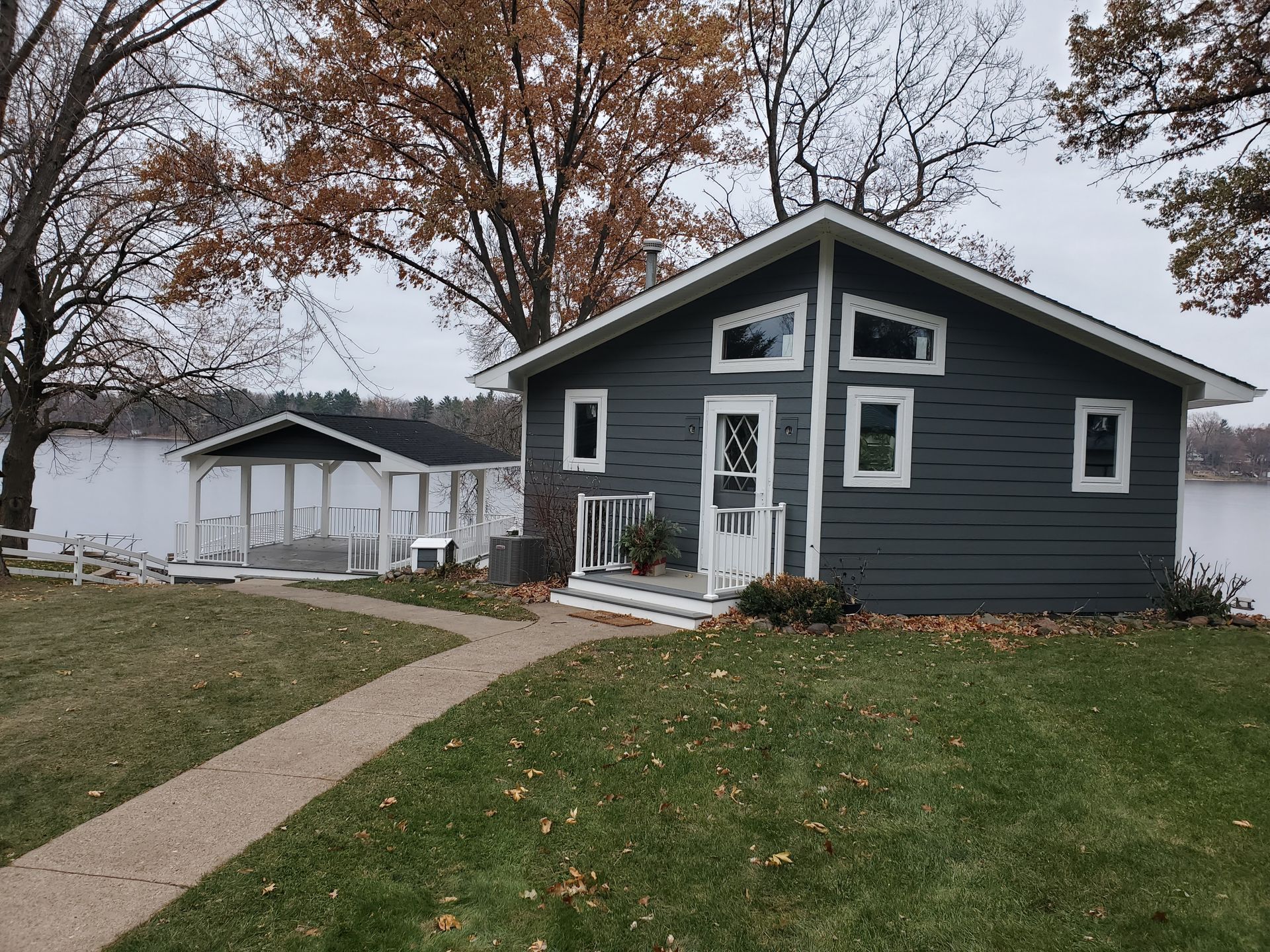 A small house with a lot of windows is next to a lake.