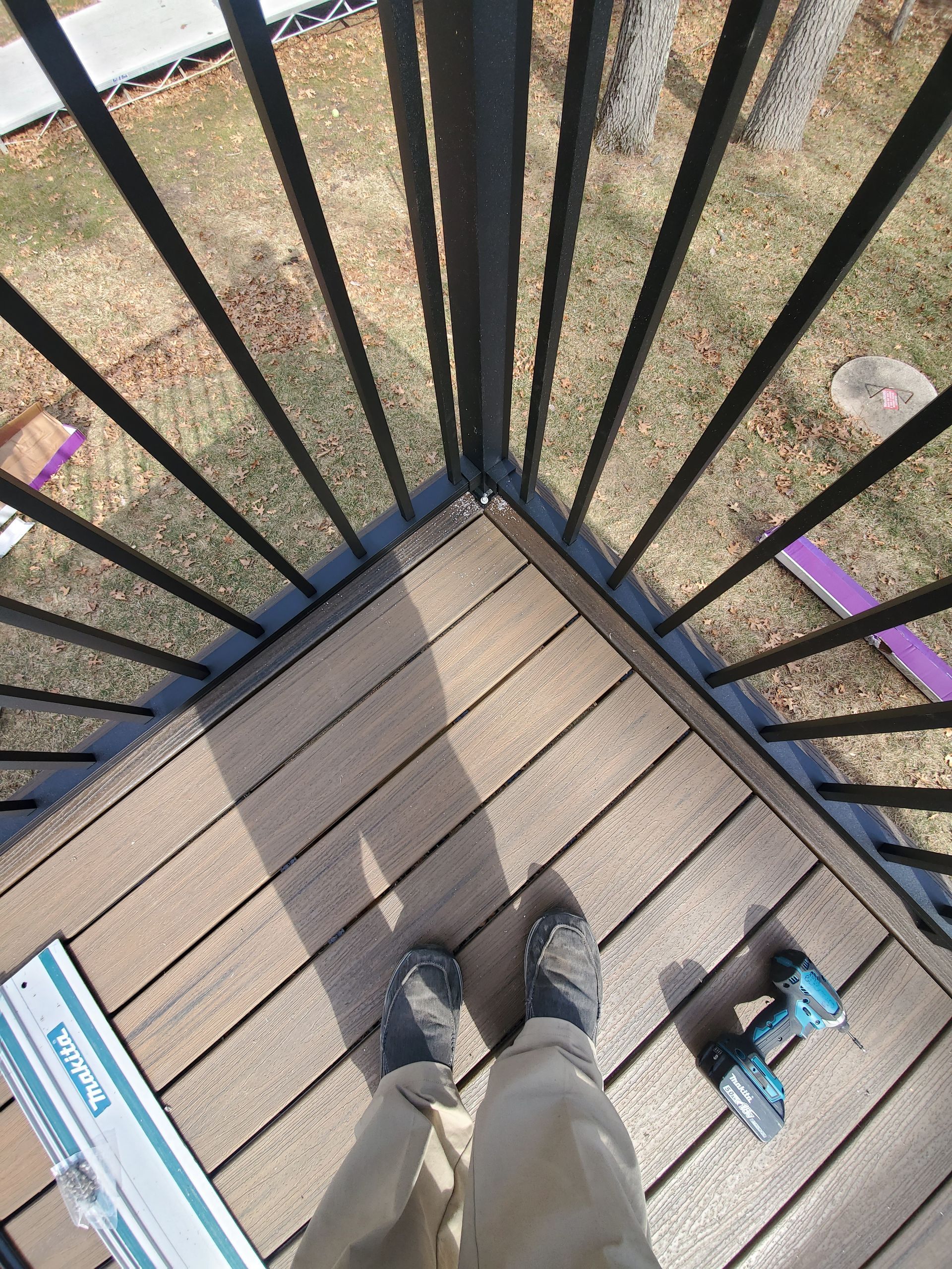 A person is standing on a wooden deck next to a metal railing.