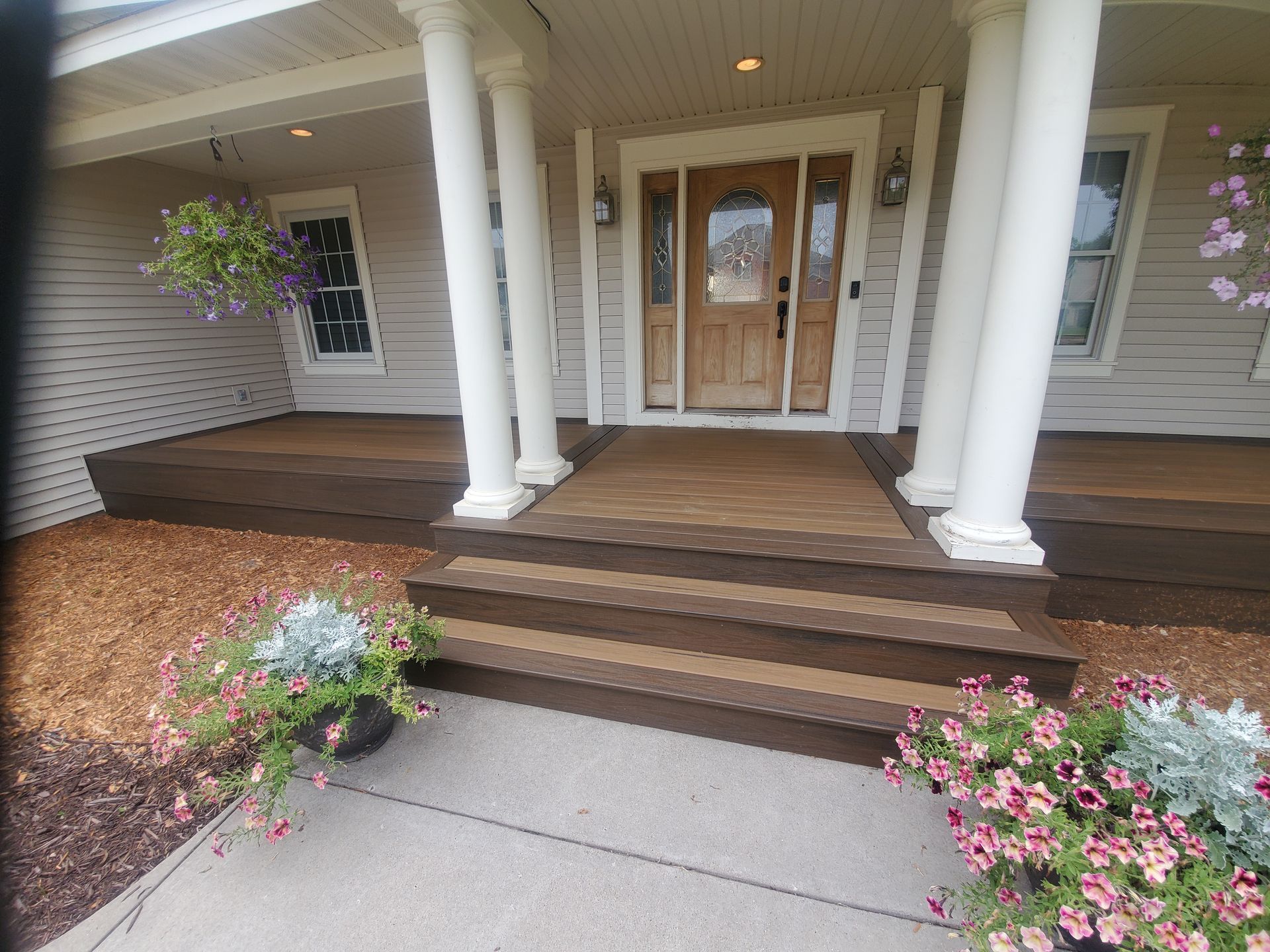 The front porch of a house with wooden steps and a wooden door.