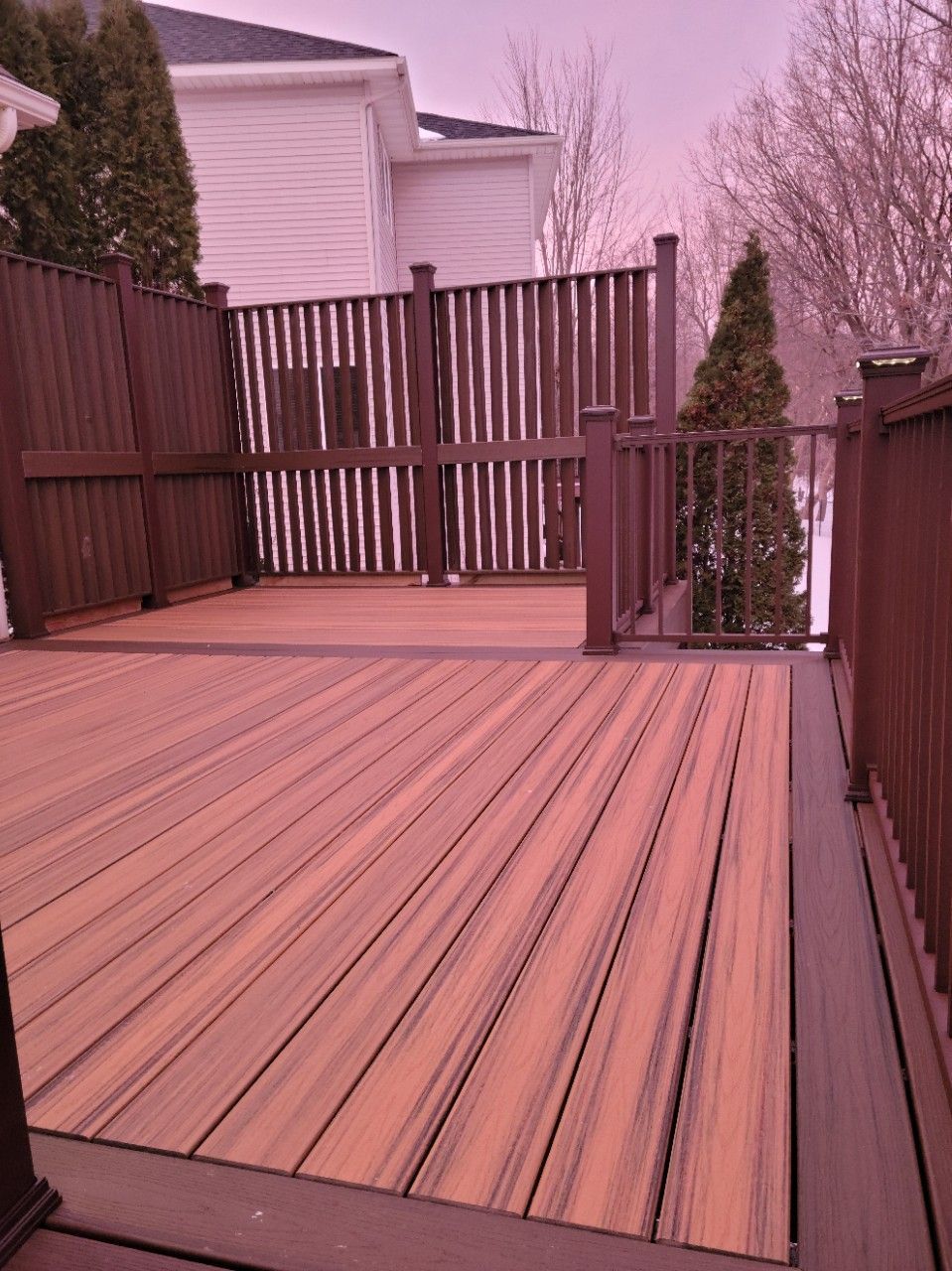 A wooden deck with a fence and a house in the background.
