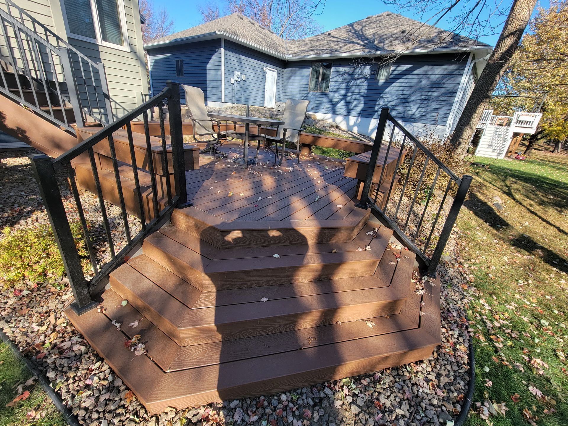 A wooden deck with stairs leading up to it in front of a house.