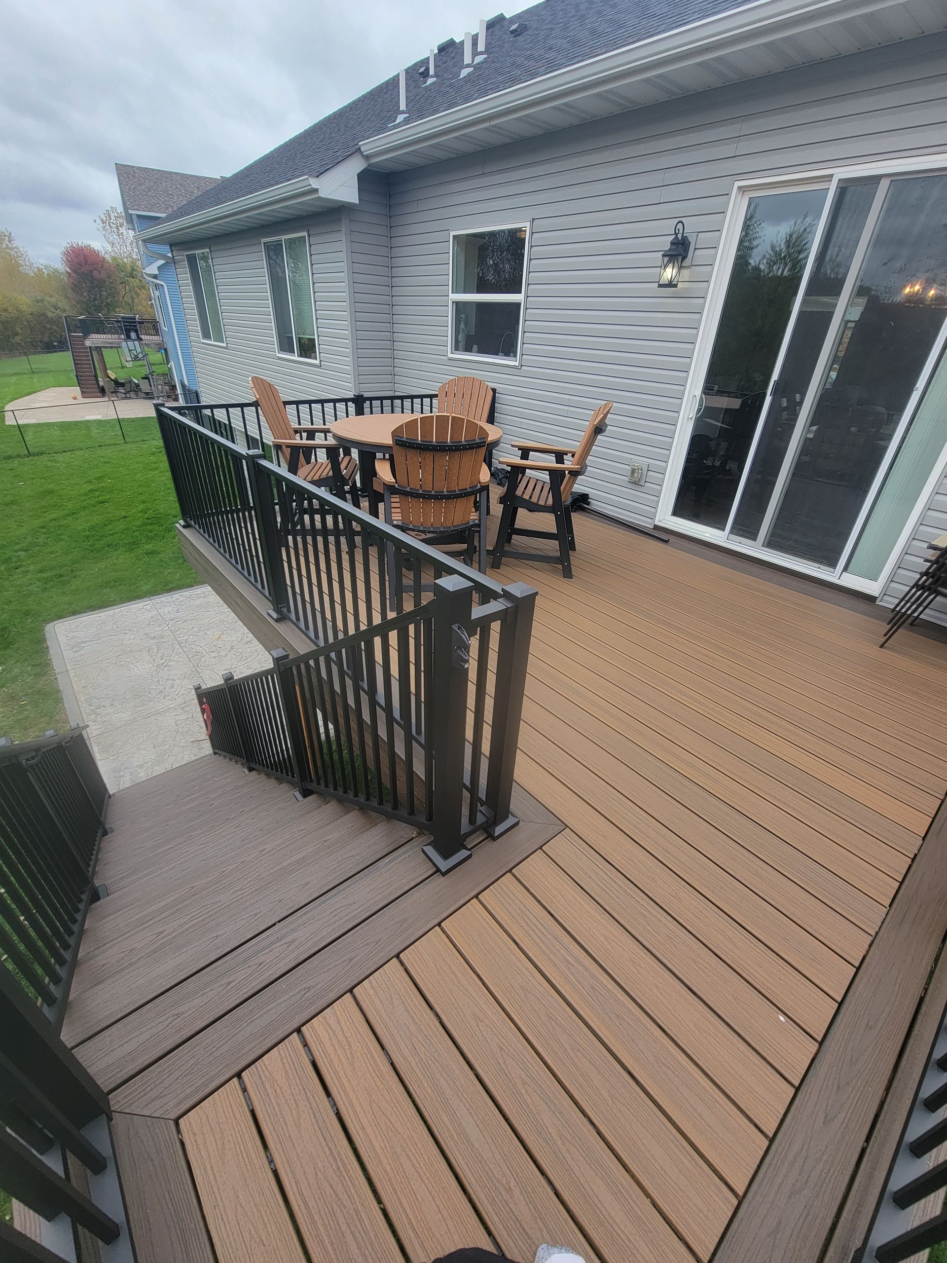 A deck with a table and chairs on it in front of a house.