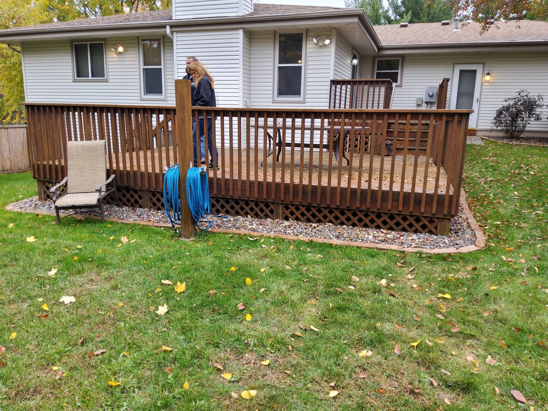 A woman is standing on a wooden deck in front of a house.