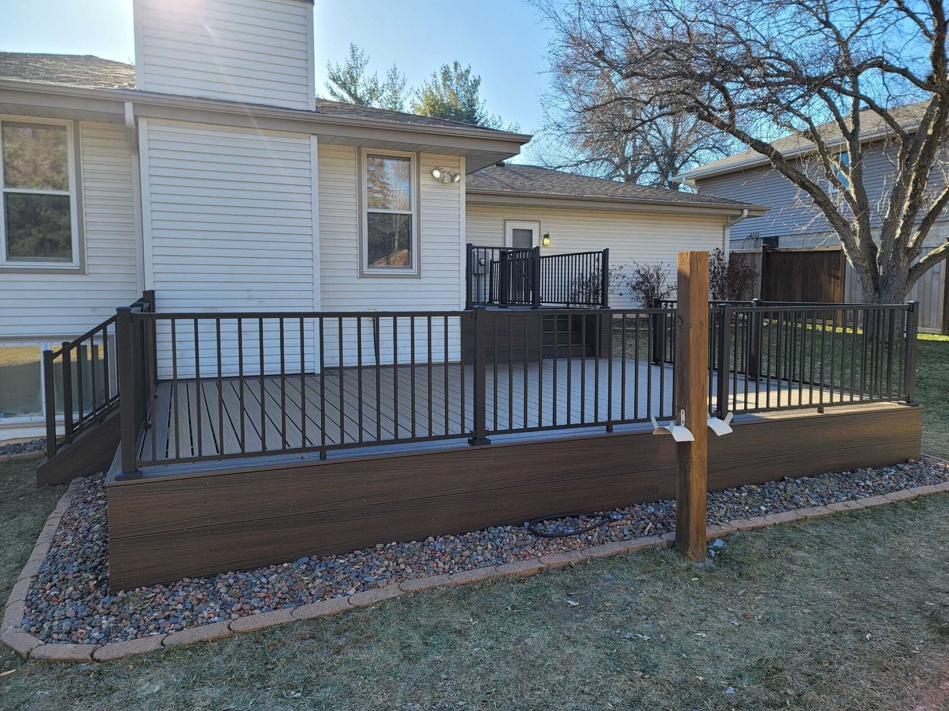 A large deck with a metal railing in front of a house.