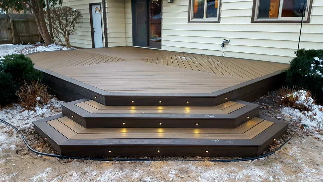 A wooden deck with stairs leading up to it in front of a house.