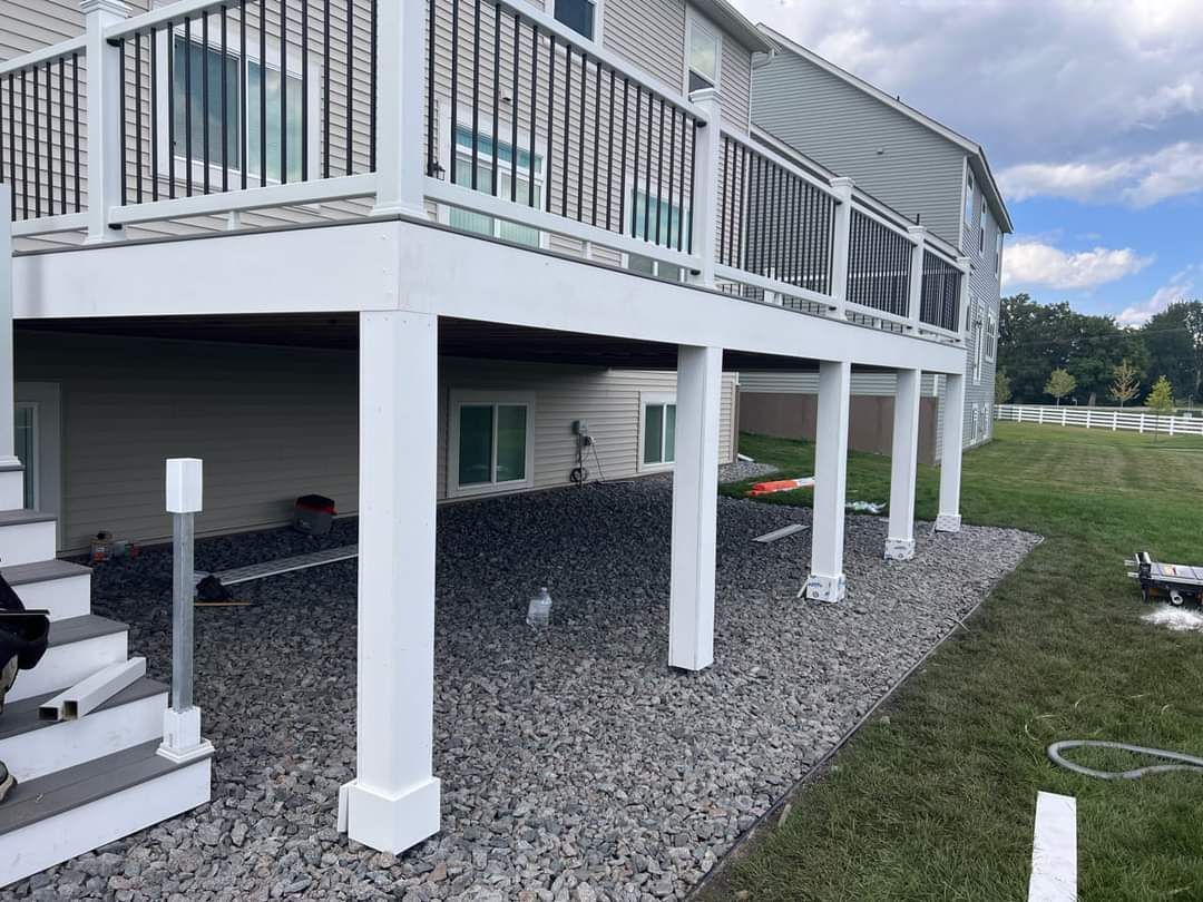 A dog is standing on the steps of a white deck.