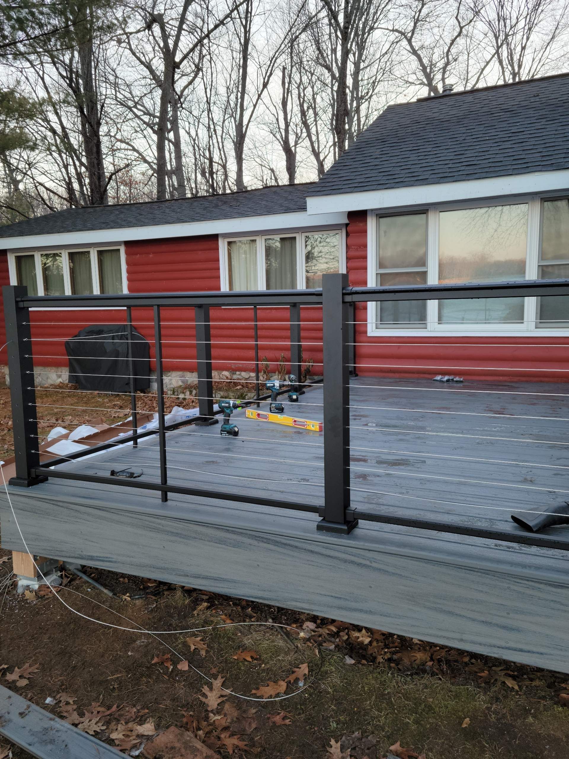A house with a deck and a fence in front of it.