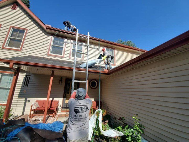 A man is standing on a ladder in front of a house.