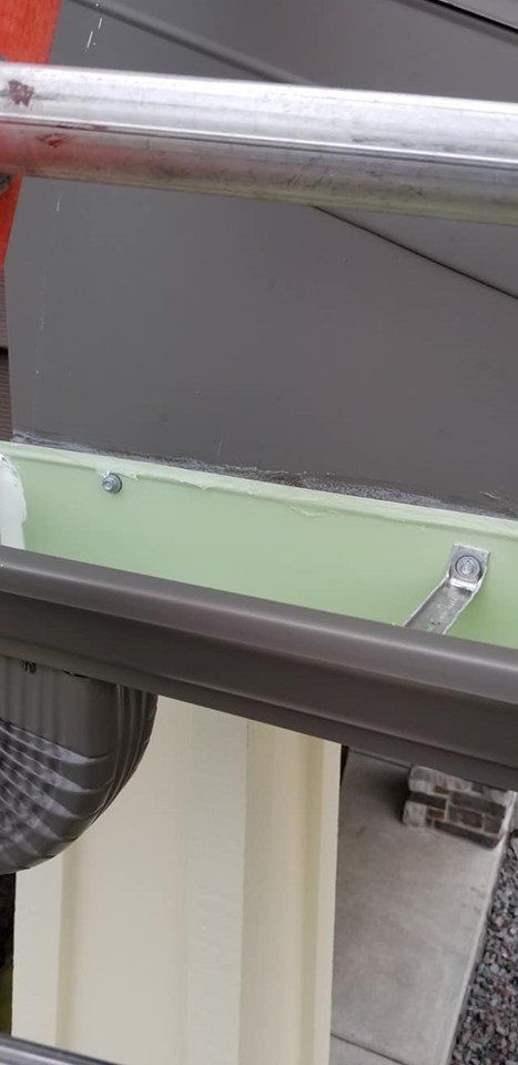 A close up of a gutter with a metal pipe attached to it.