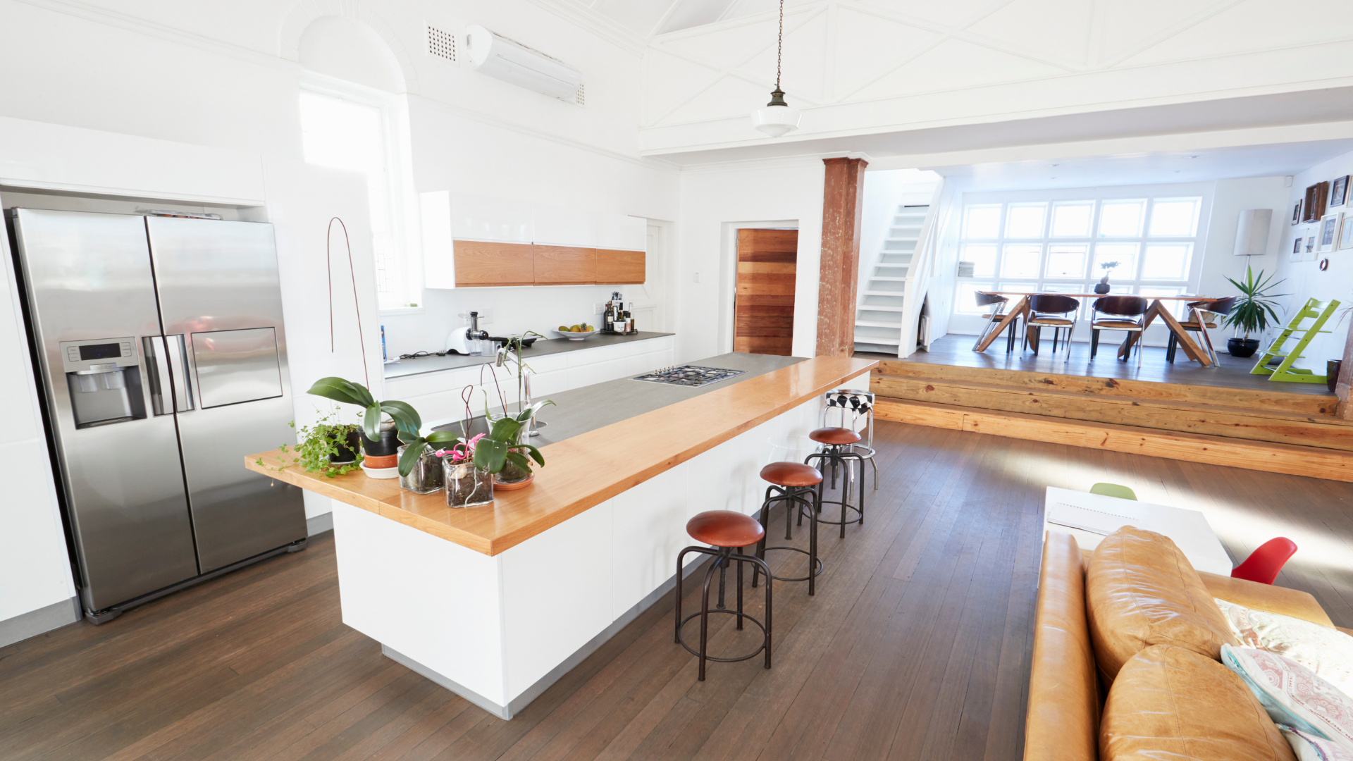Room with brown walls, white trim and ceiling, three windows, and a ceiling fan. Paint supplies cover the floor.
