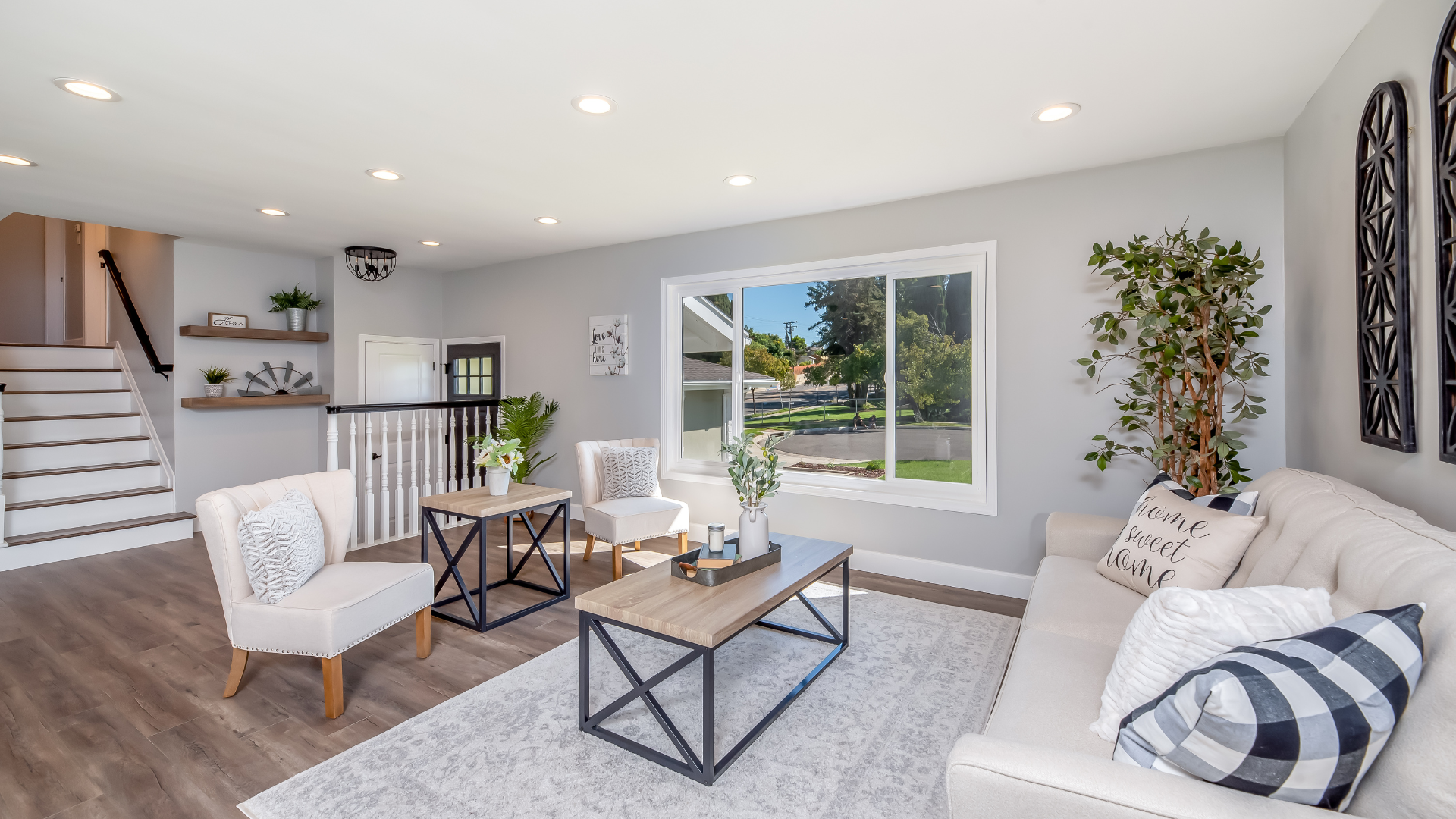 Bright living room with white furniture, gray walls, and a view of the outdoors.