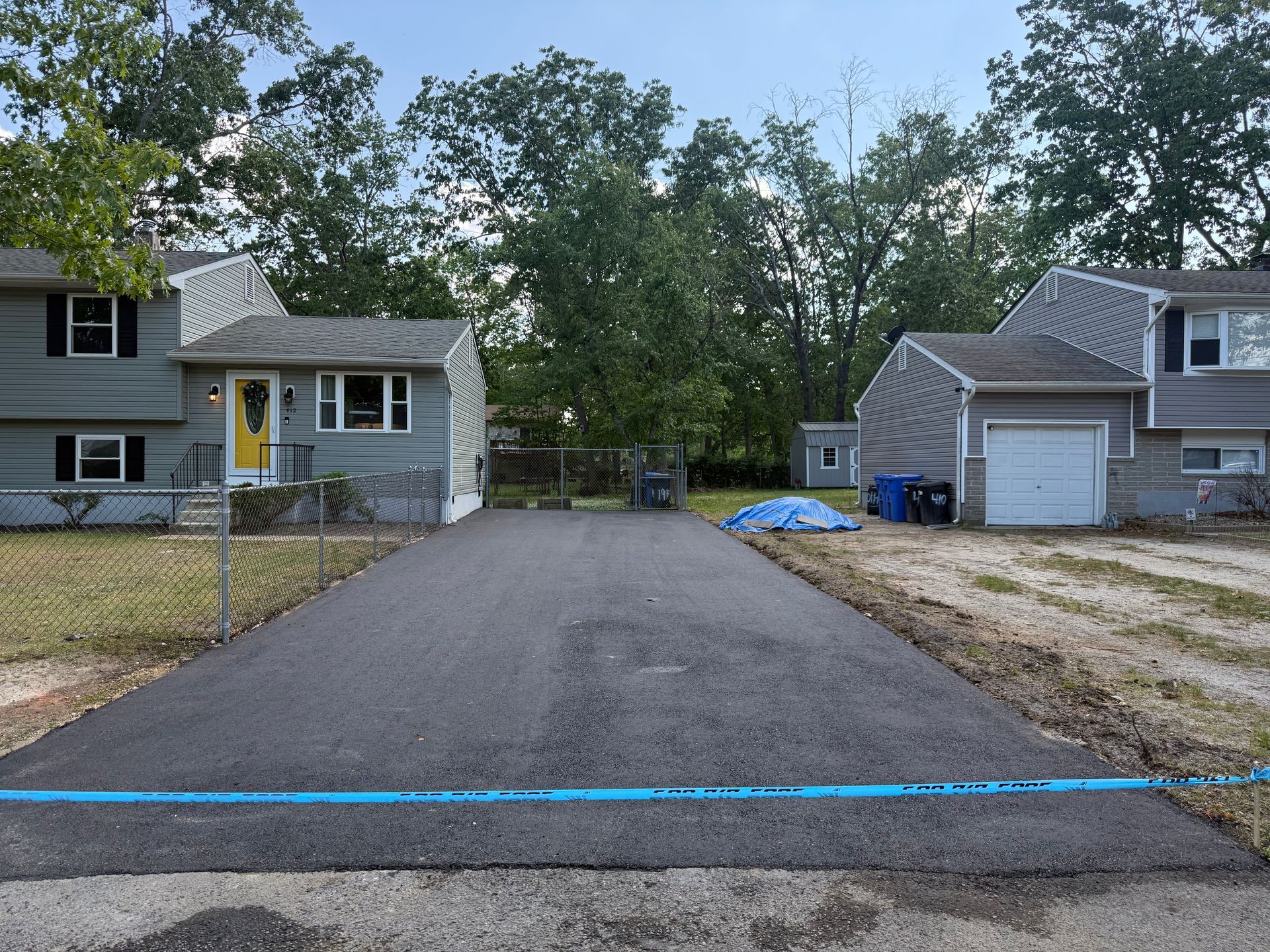 Freshly paved driveway between two houses, viewed from the street.