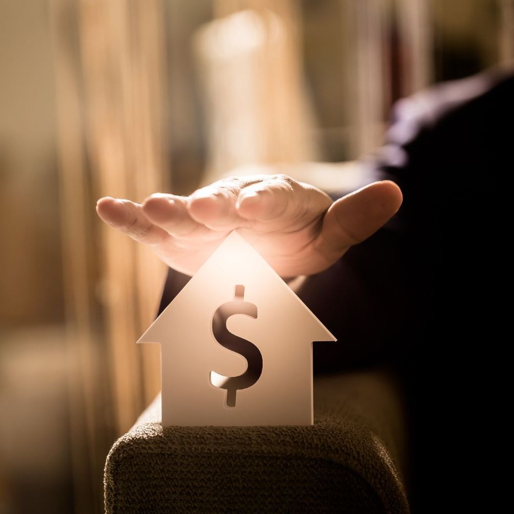 A hand is holding a small house with a dollar sign on it for Fraser Corporate Finance.