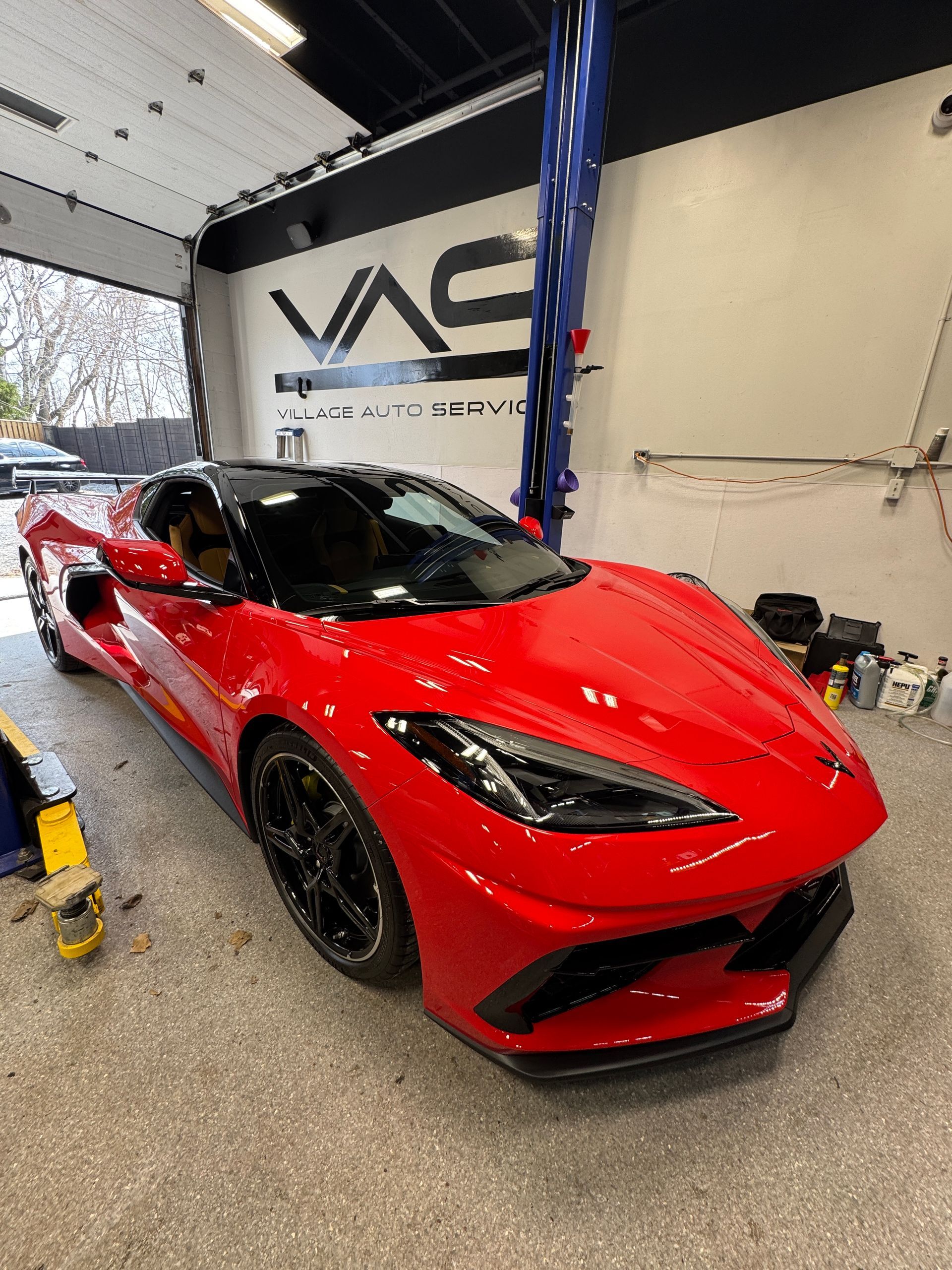 A red Corvette parked inside Village Auto Service
