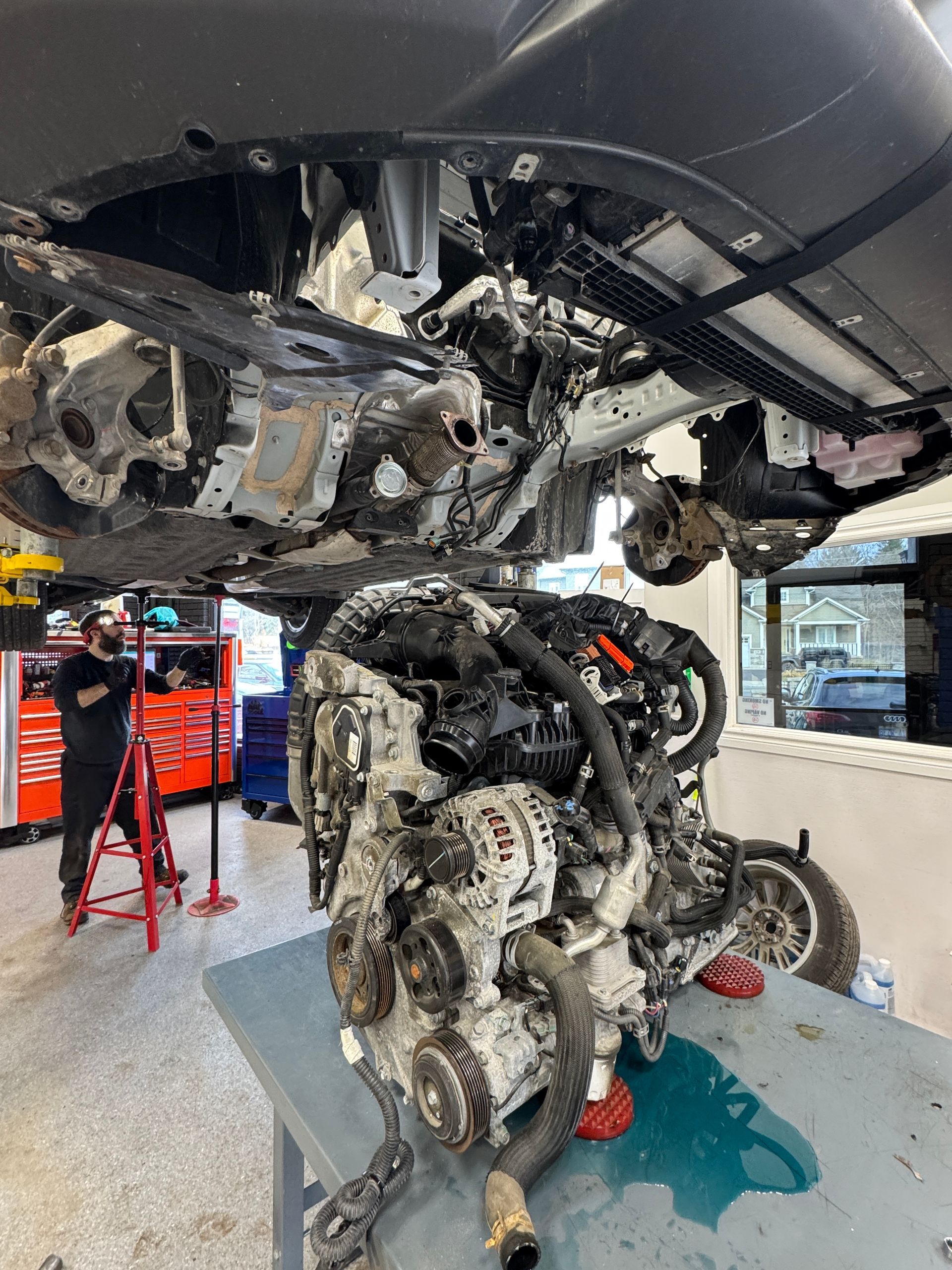 A car raised above an exposed engine because it's in our shop getting an engine swap service