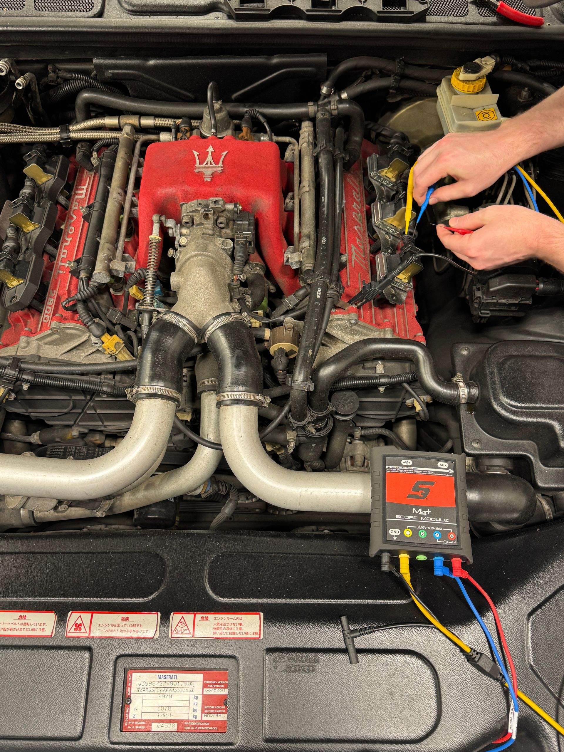 Mechanic at Village Auto service doing diagnostics on the engine of a Maserati