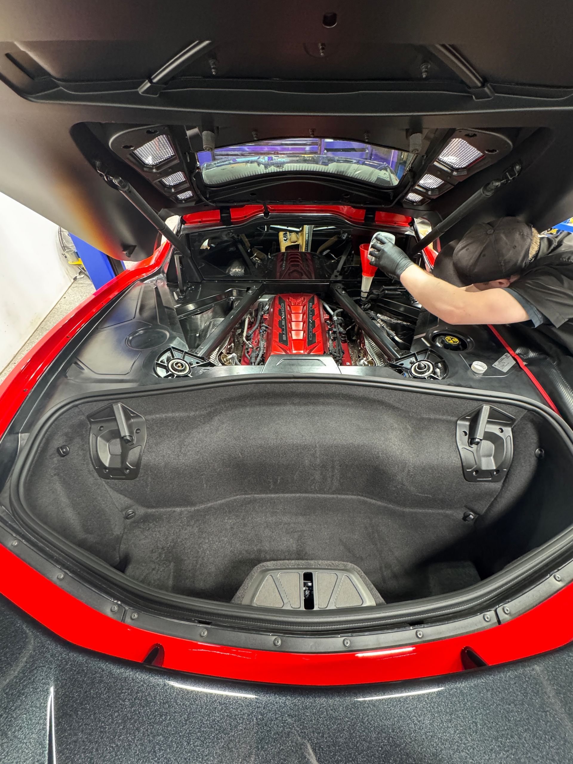 An exotic vehicle is getting new synthetic oil poured into its engine at Village Auto Service