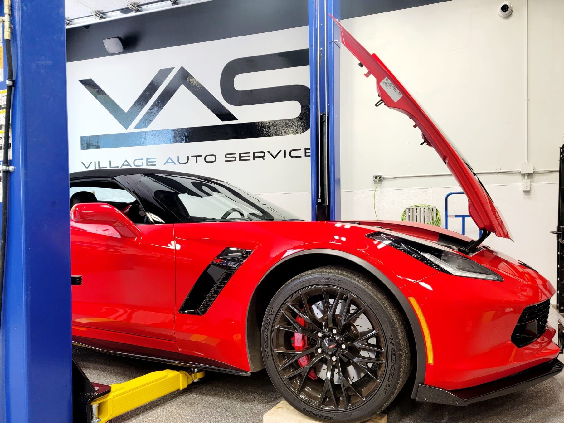 Get expert car tune ups with Village Auto Service red vehicle with hood open for maintenance in auto shop