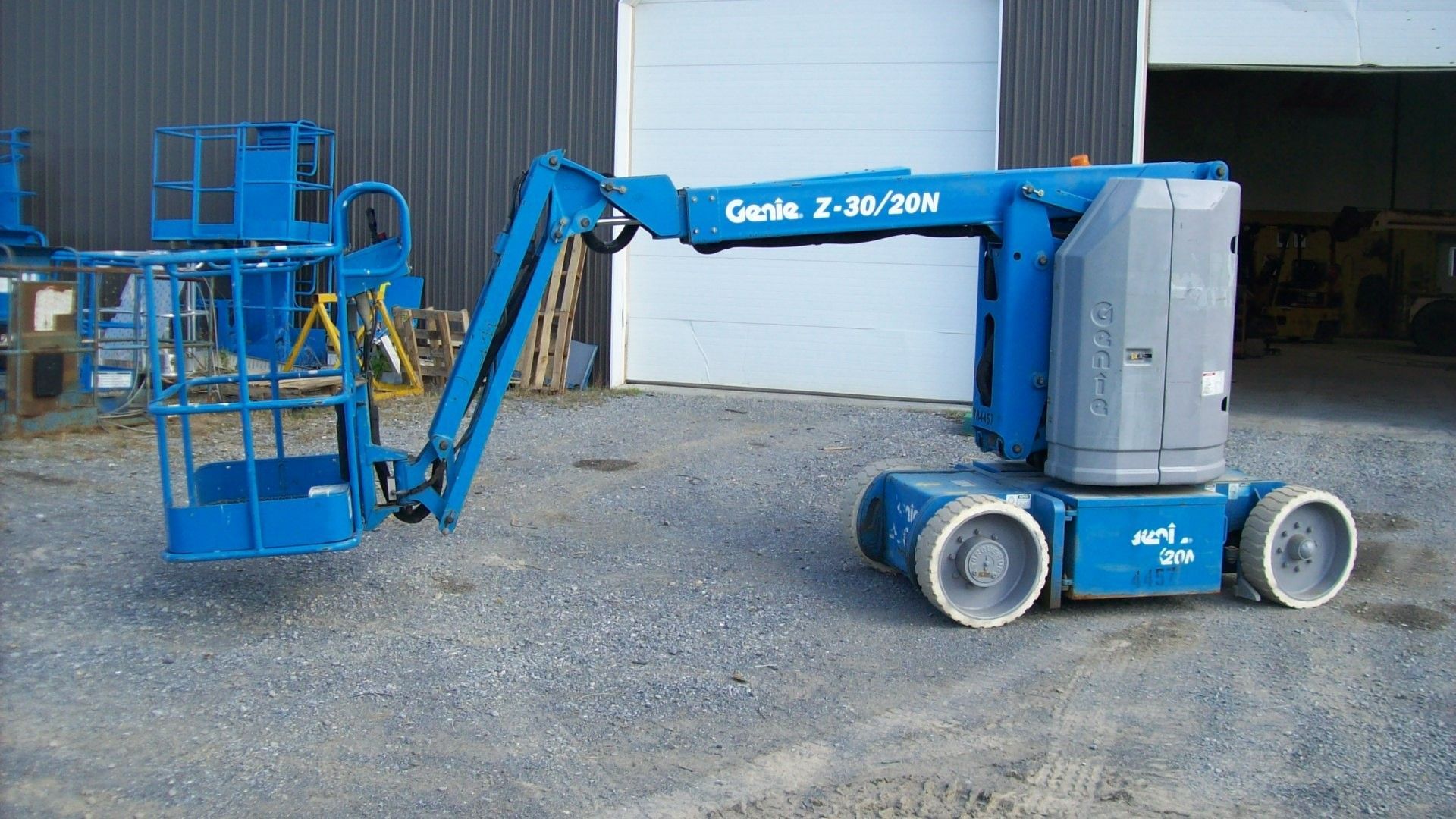 A genie lift is parked in front of a garage door