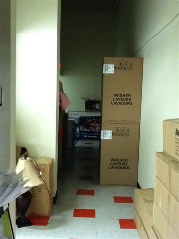 A hallway filled with boxes that say washer and dryer