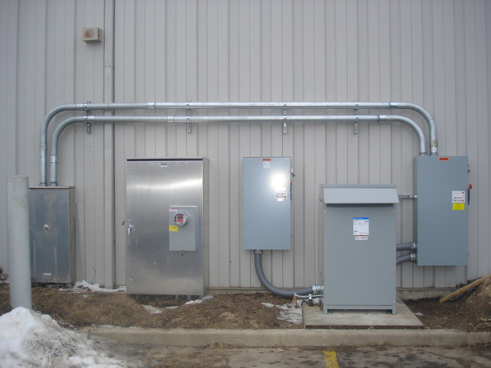 There are a lot of electrical boxes on the side of a building.