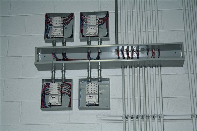 A bunch of electrical boxes are hanging on a wall