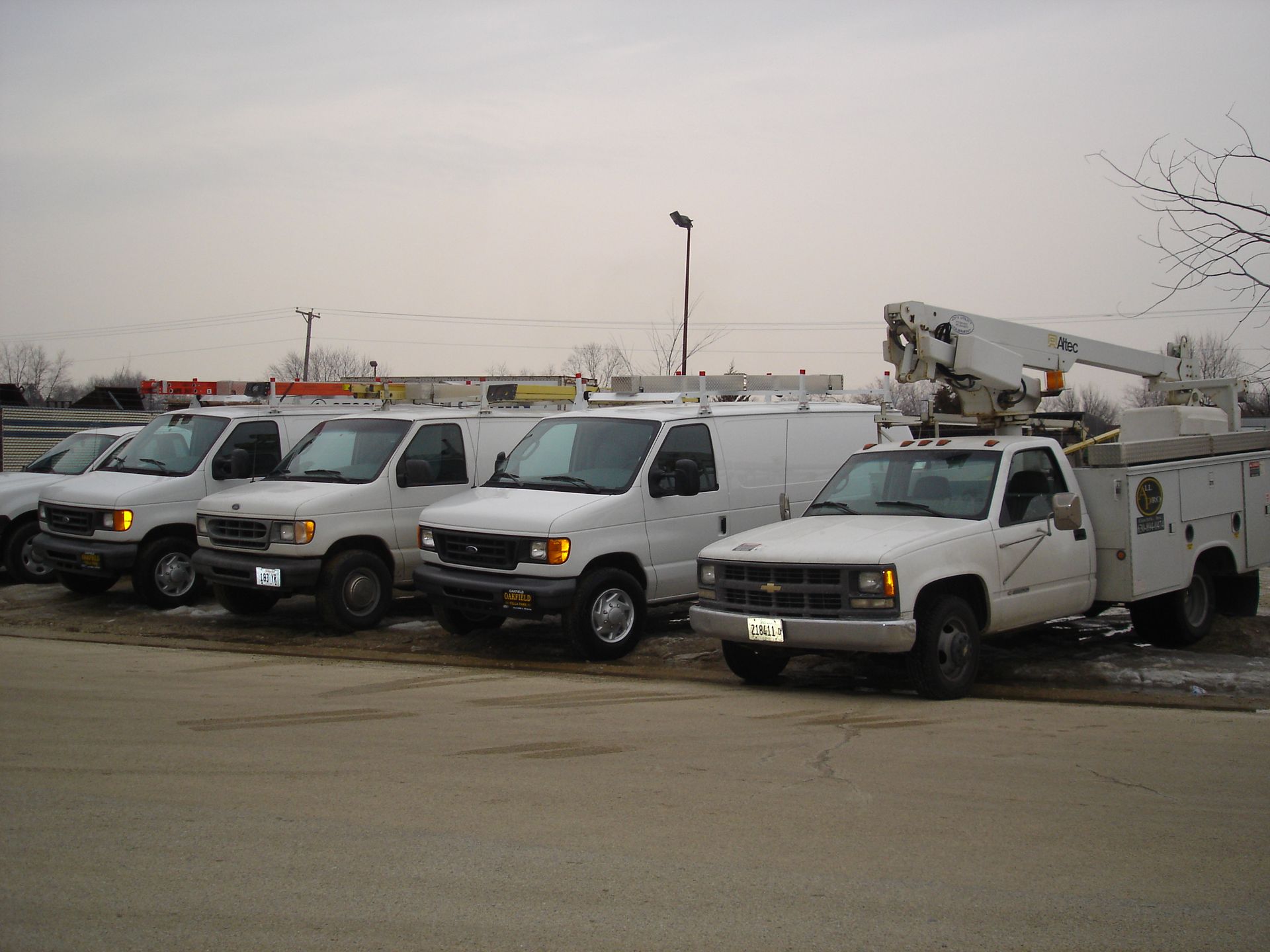 A row of utility trucks are parked in a parking lot