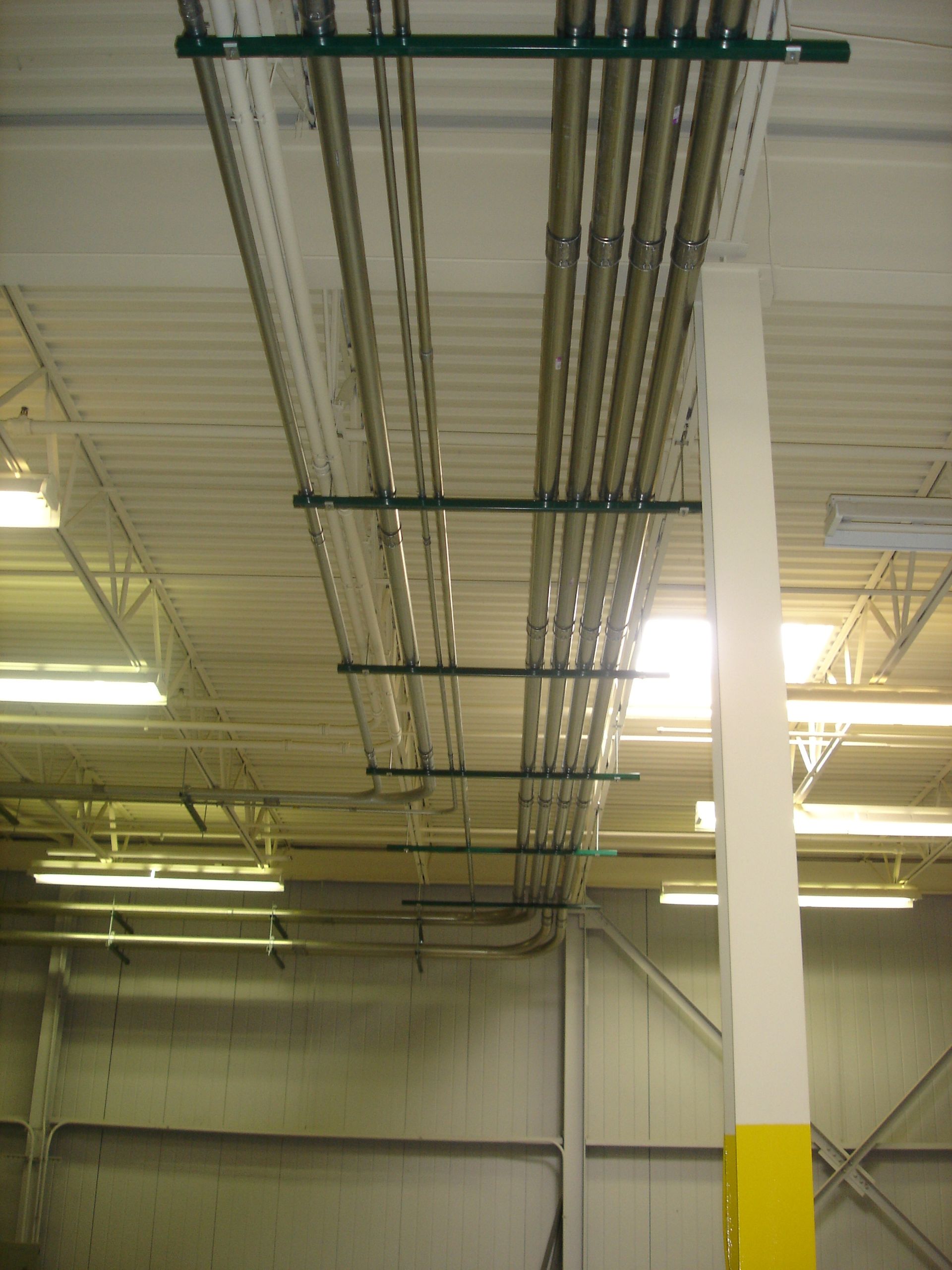 A bunch of pipes are hanging from the ceiling of a building