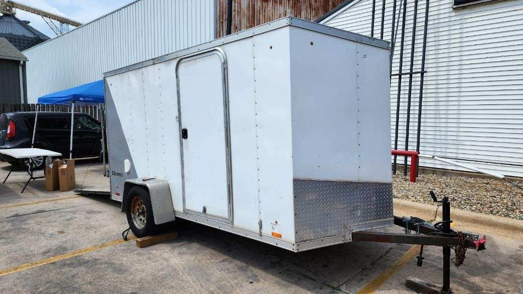 A white trailer is parked in a parking lot in front of a building.