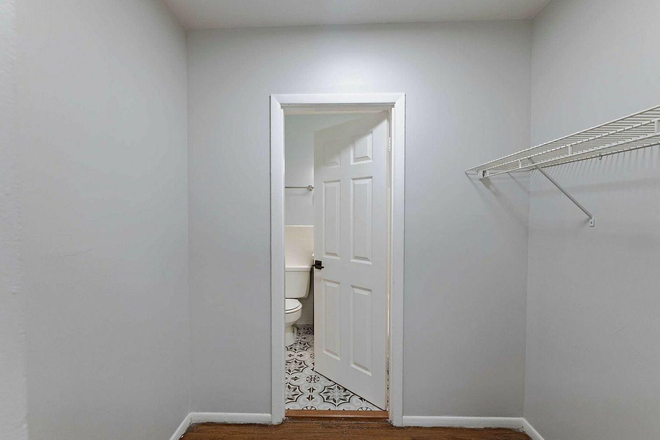 A walk in closet with a toilet and a door leading to a bathroom.