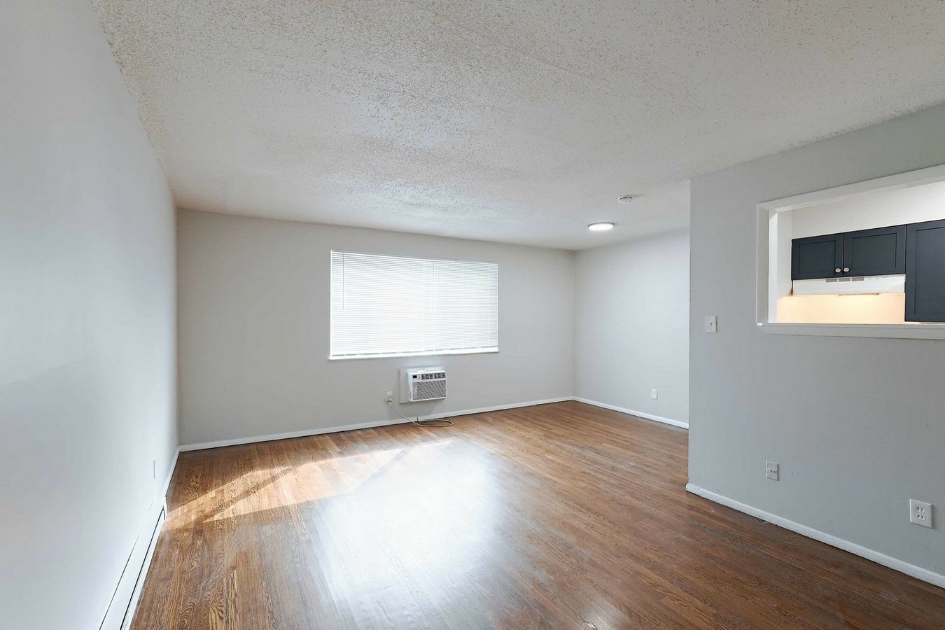 An empty living room with hardwood floors and a window.