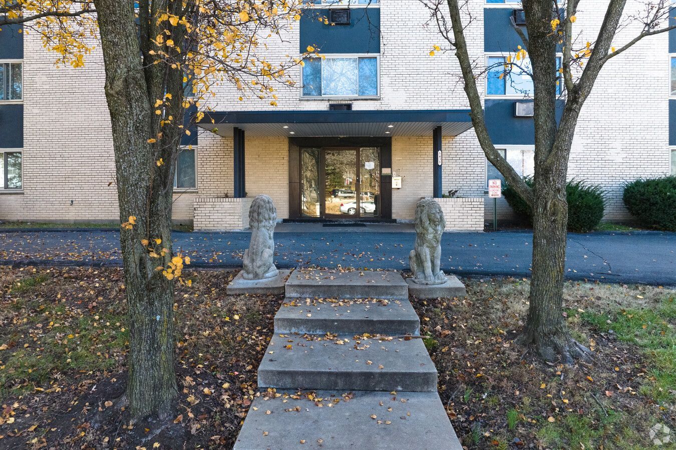 A building with a staircase leading to the entrance and a statue of a lion in front of it.