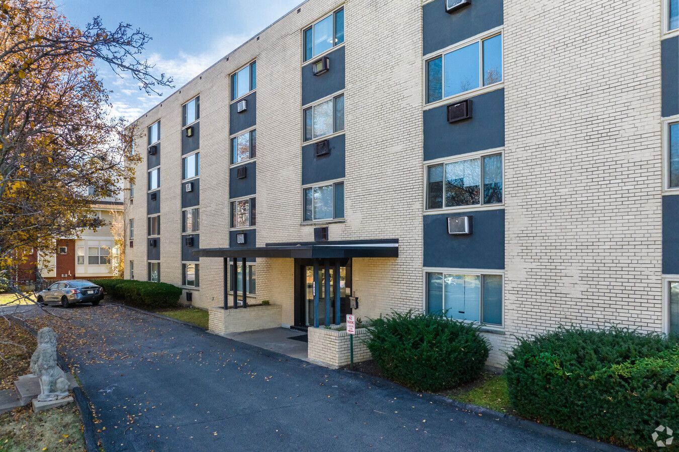 A large apartment building with a lot of windows and a car parked in front of it.