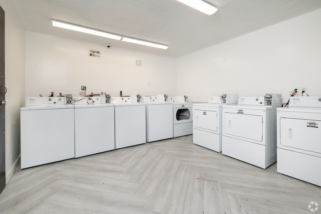 A laundry room with a lot of white washers and dryers