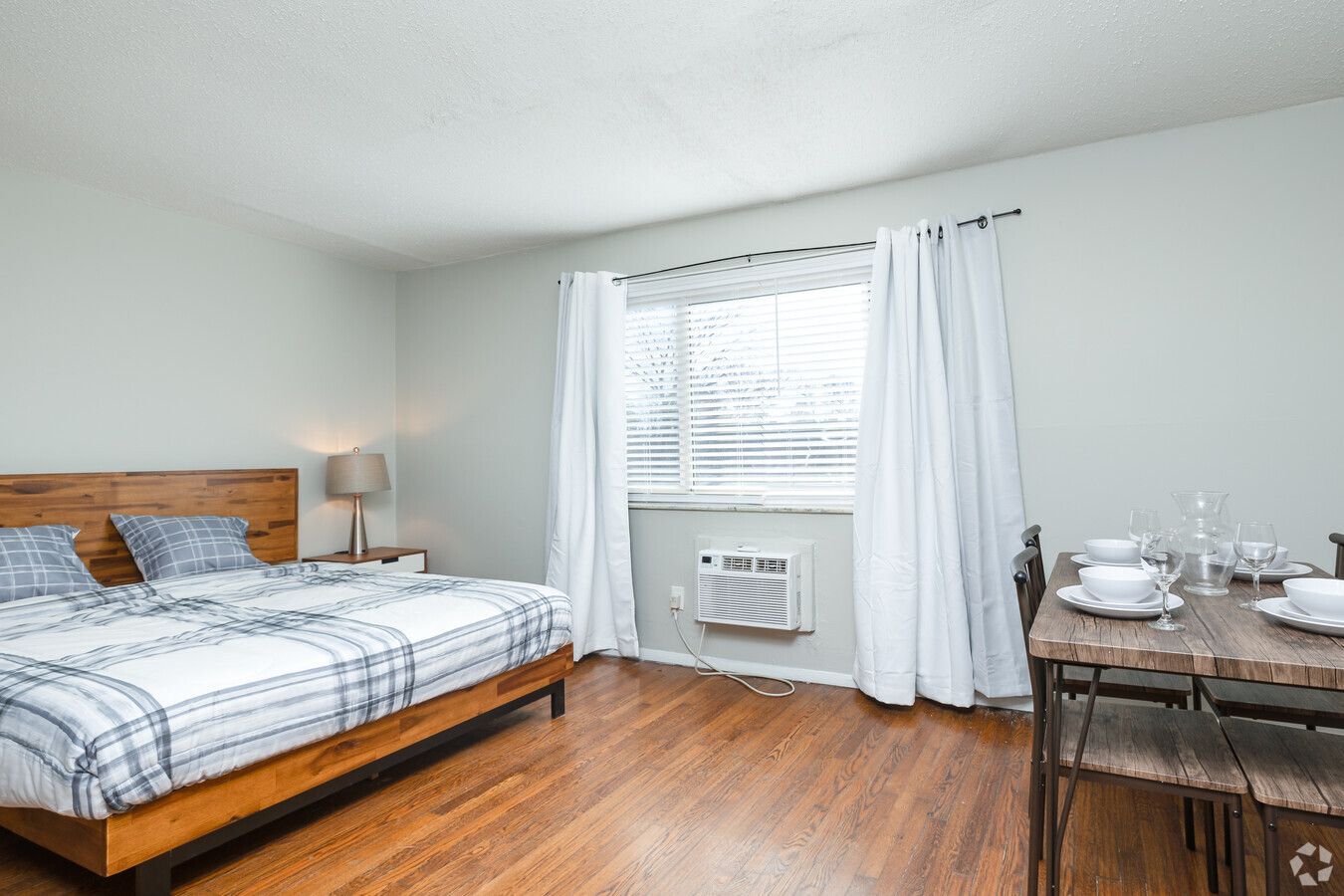A bedroom with a bed , dining table and chairs.