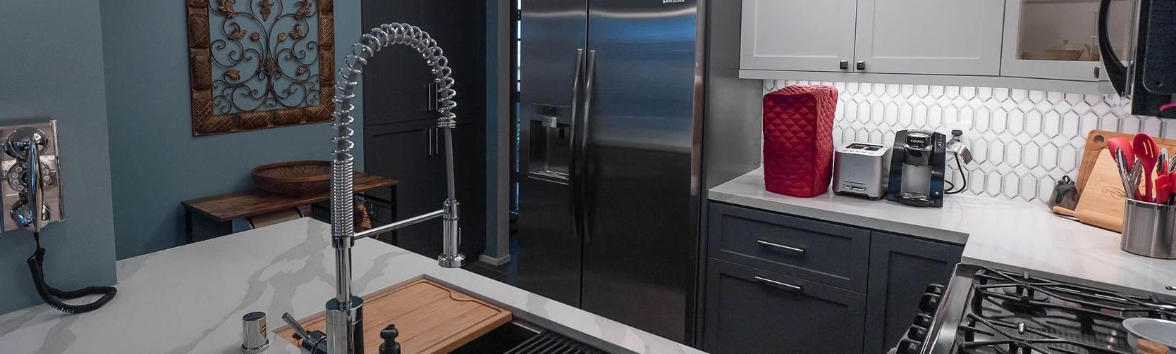 A kitchen with a sink , refrigerator and microwave.