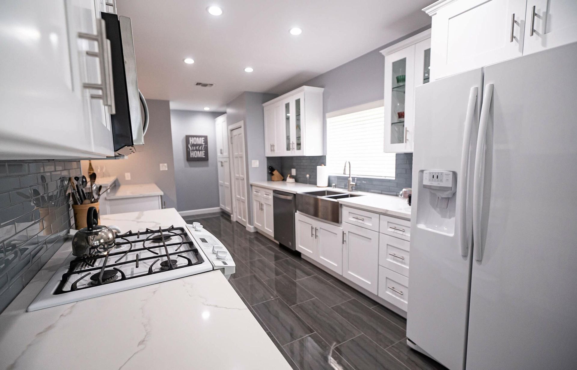 A kitchen with white cabinets , a stove , a refrigerator , and a sink.