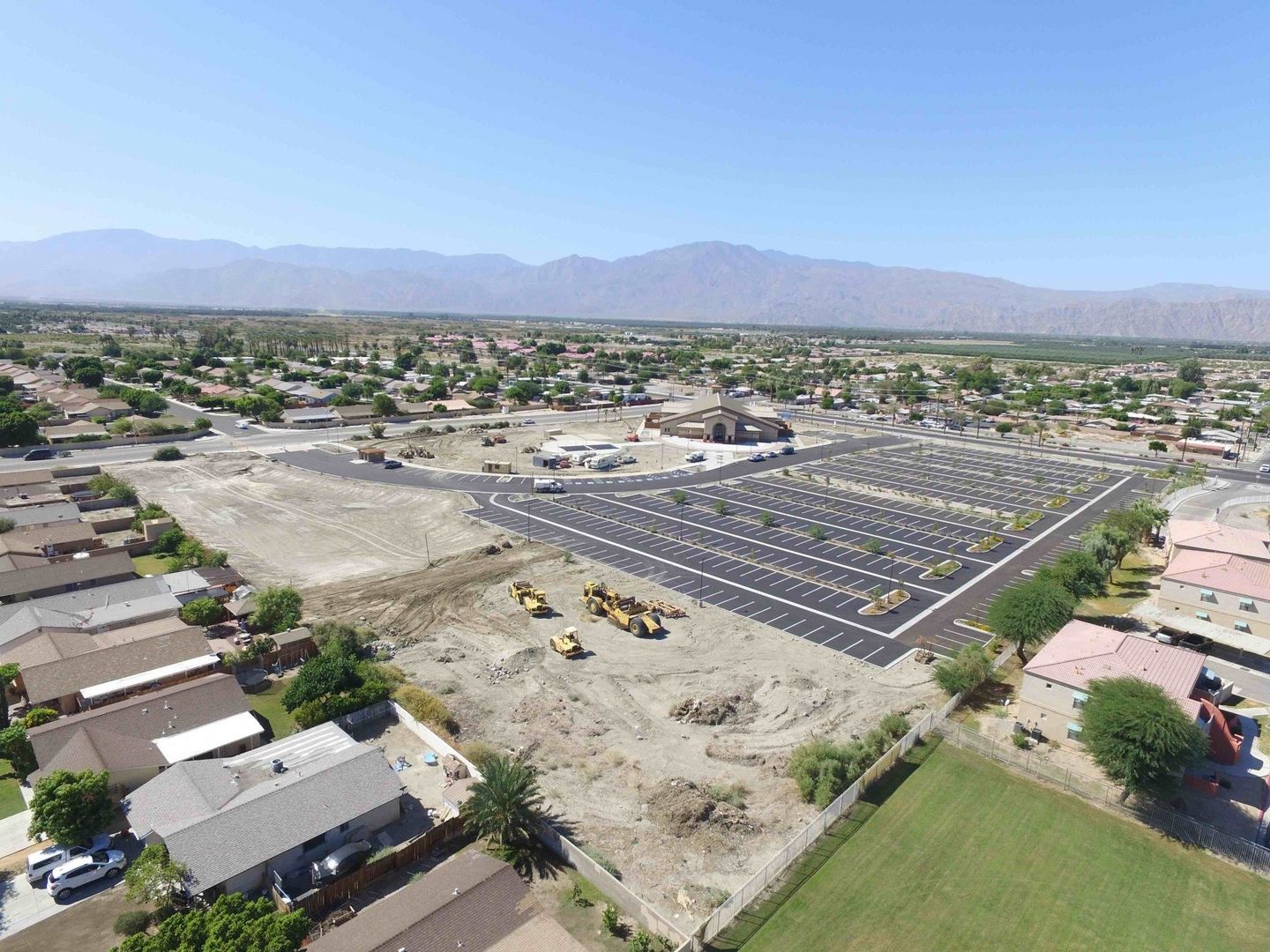Mckeever Civil Engineering's  aerial view of a completed project of a parking lot in a residential area with mountains in the background .