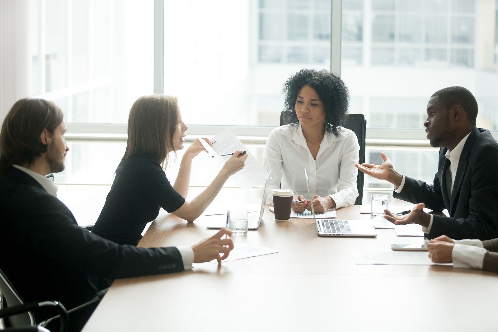 A group of people are sitting around a table having a meeting.