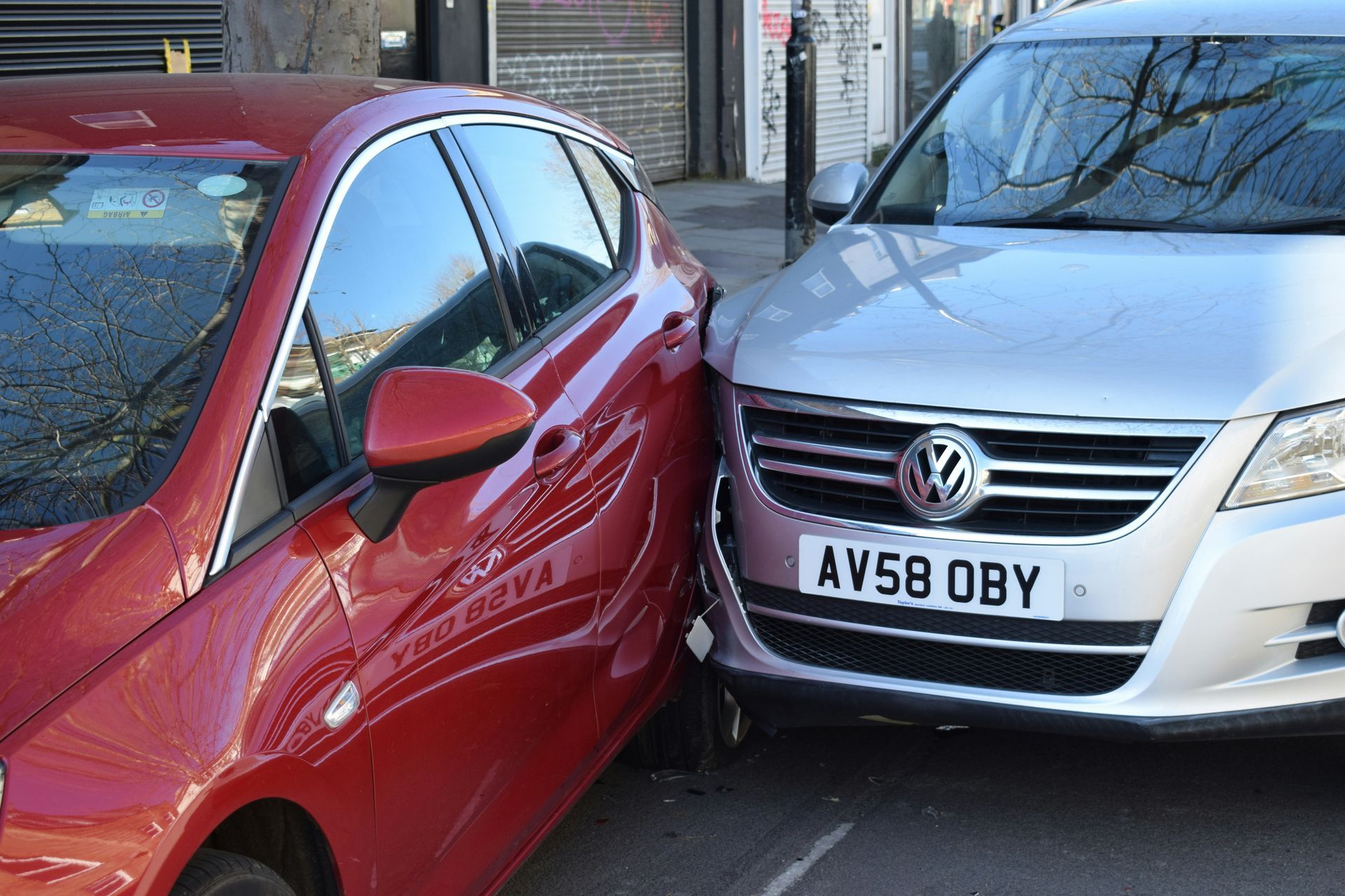 A man is standing next to a car that has crashed into another car.