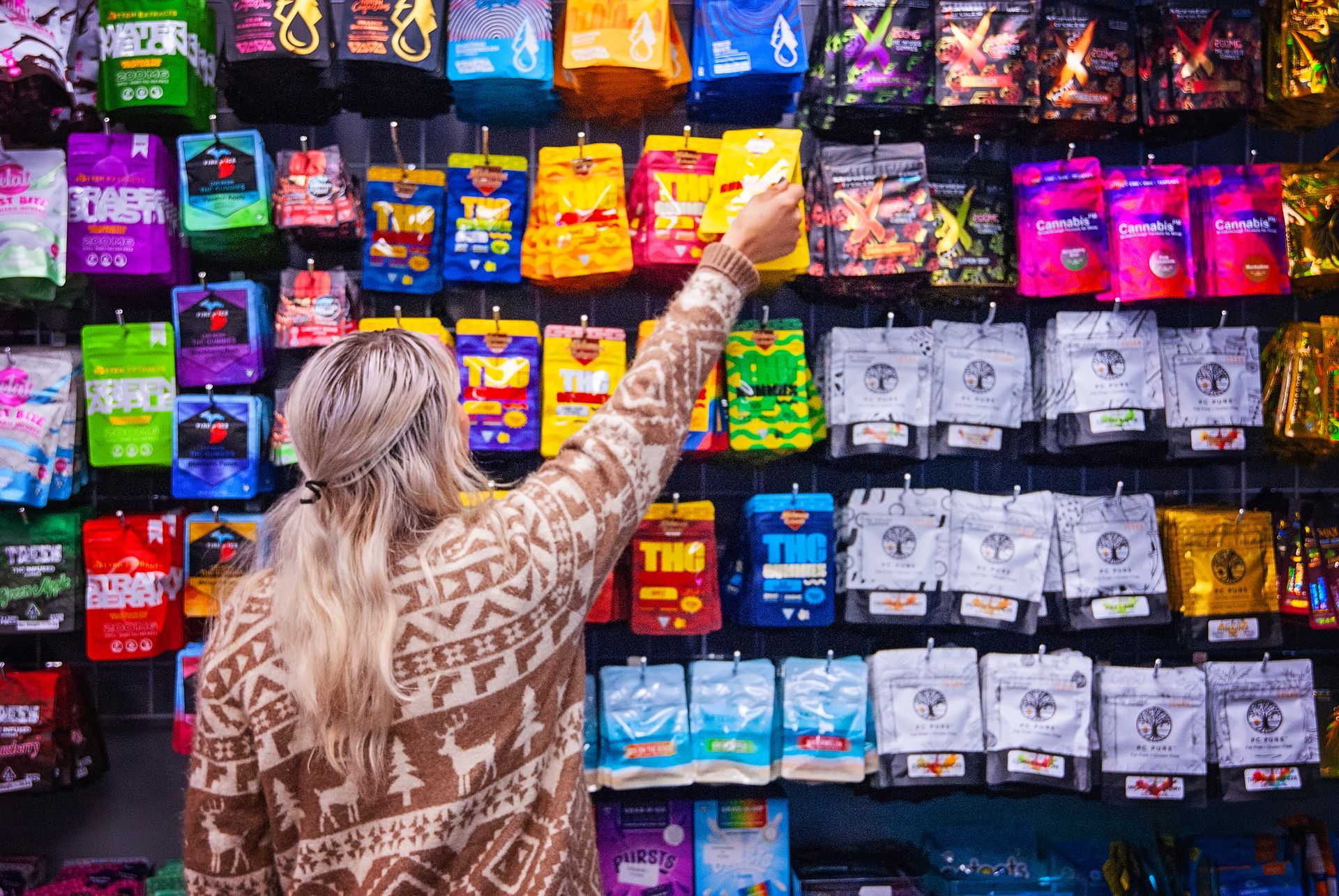 A woman is standing in front of a wall of gift cards in a store.