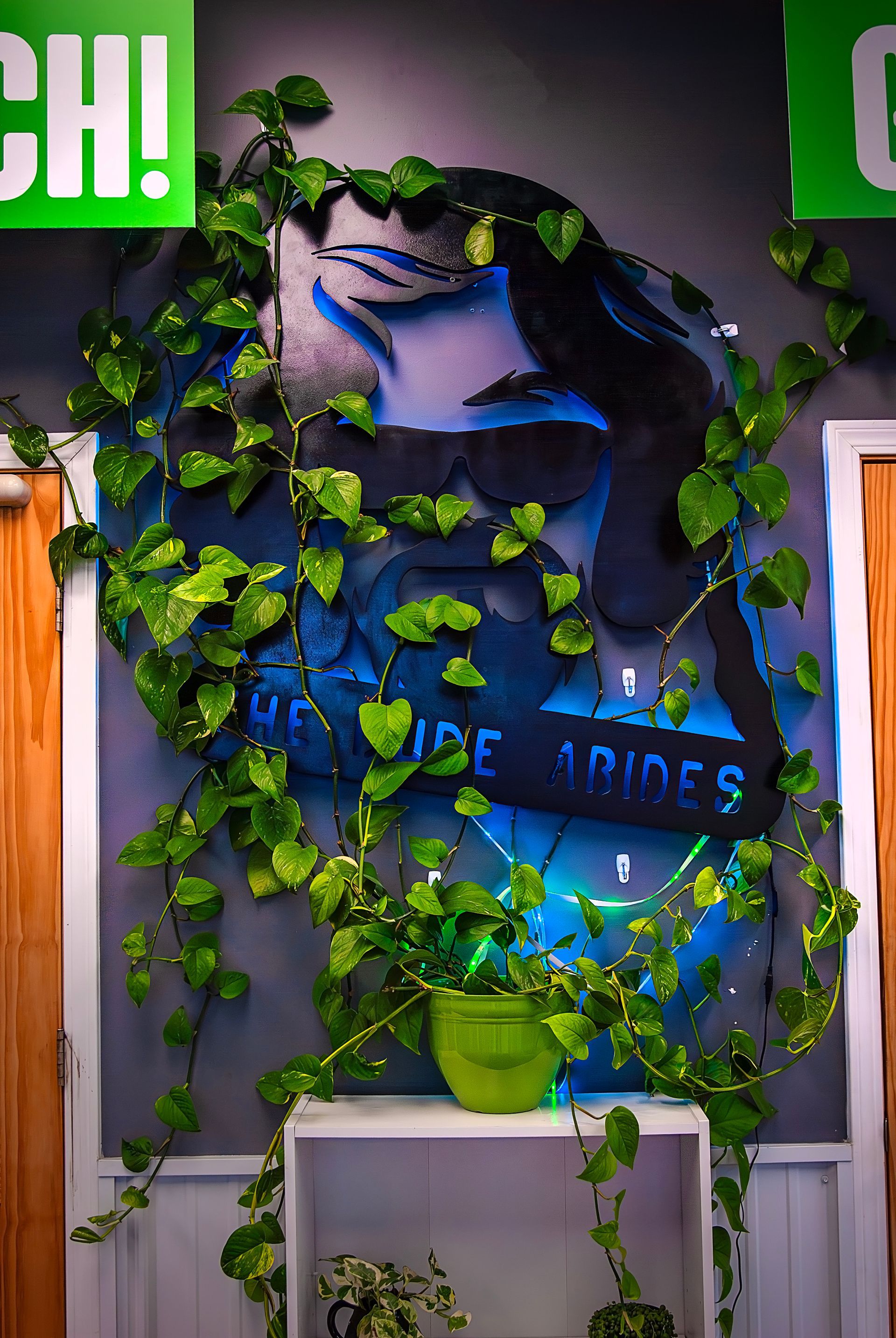 A painting of a woman 's face is surrounded by ivy and a potted plant.