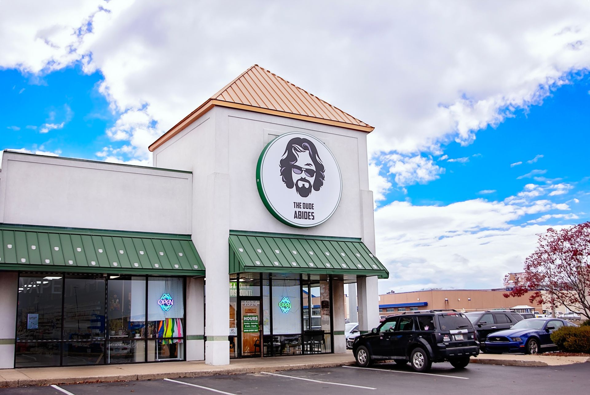 A car is parked in front of a store with a bearded man on the front.
