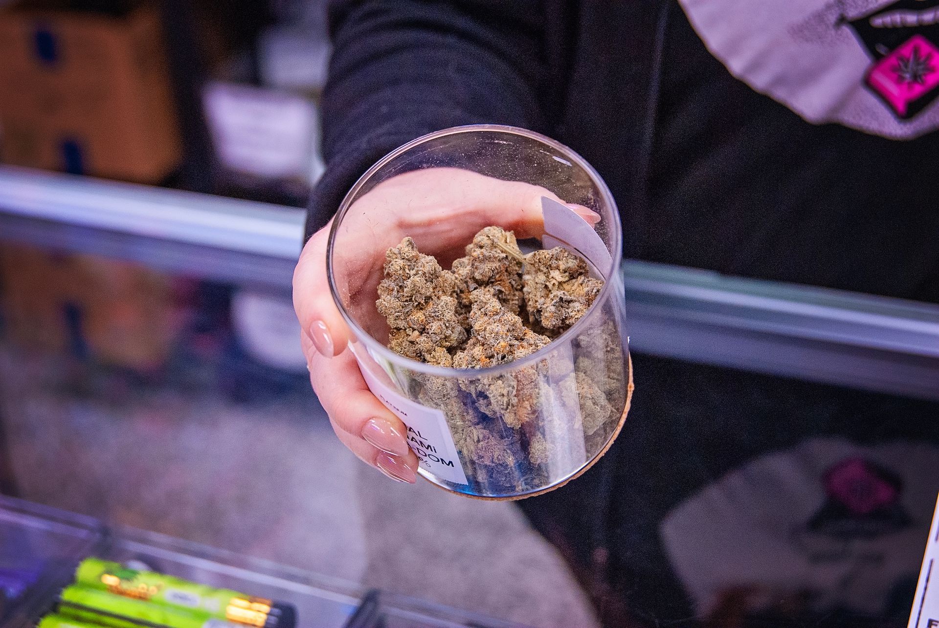 A person is holding a glass filled with weed in their hand.