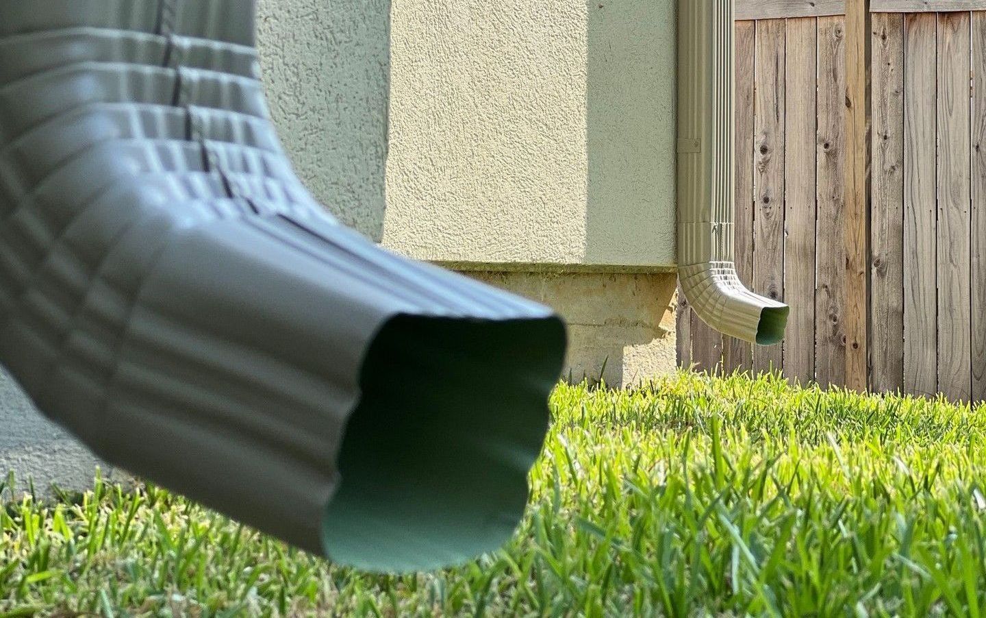 a gutter is sitting in the grass in front of a house .