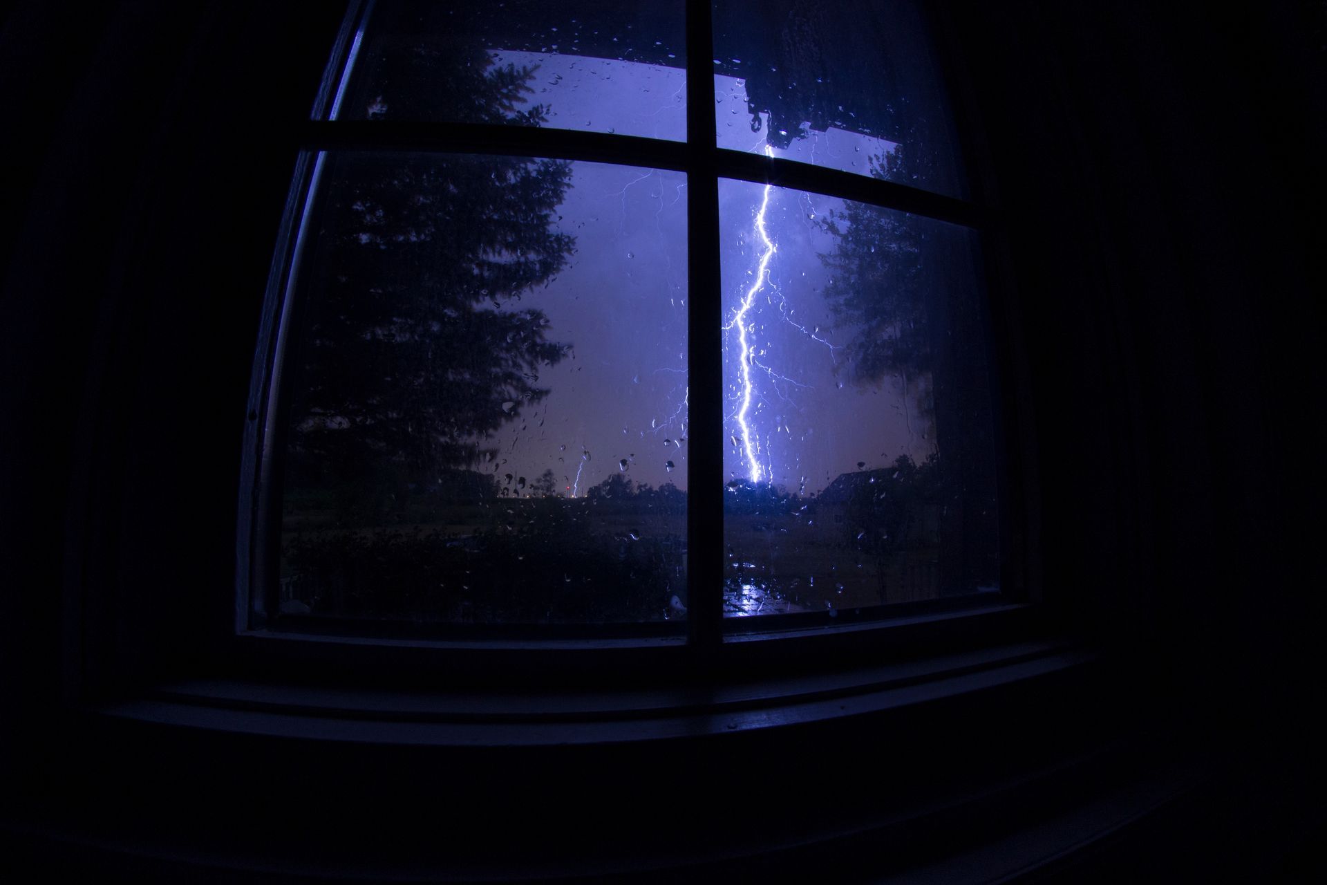 a lightning bolt is visible through a window at night