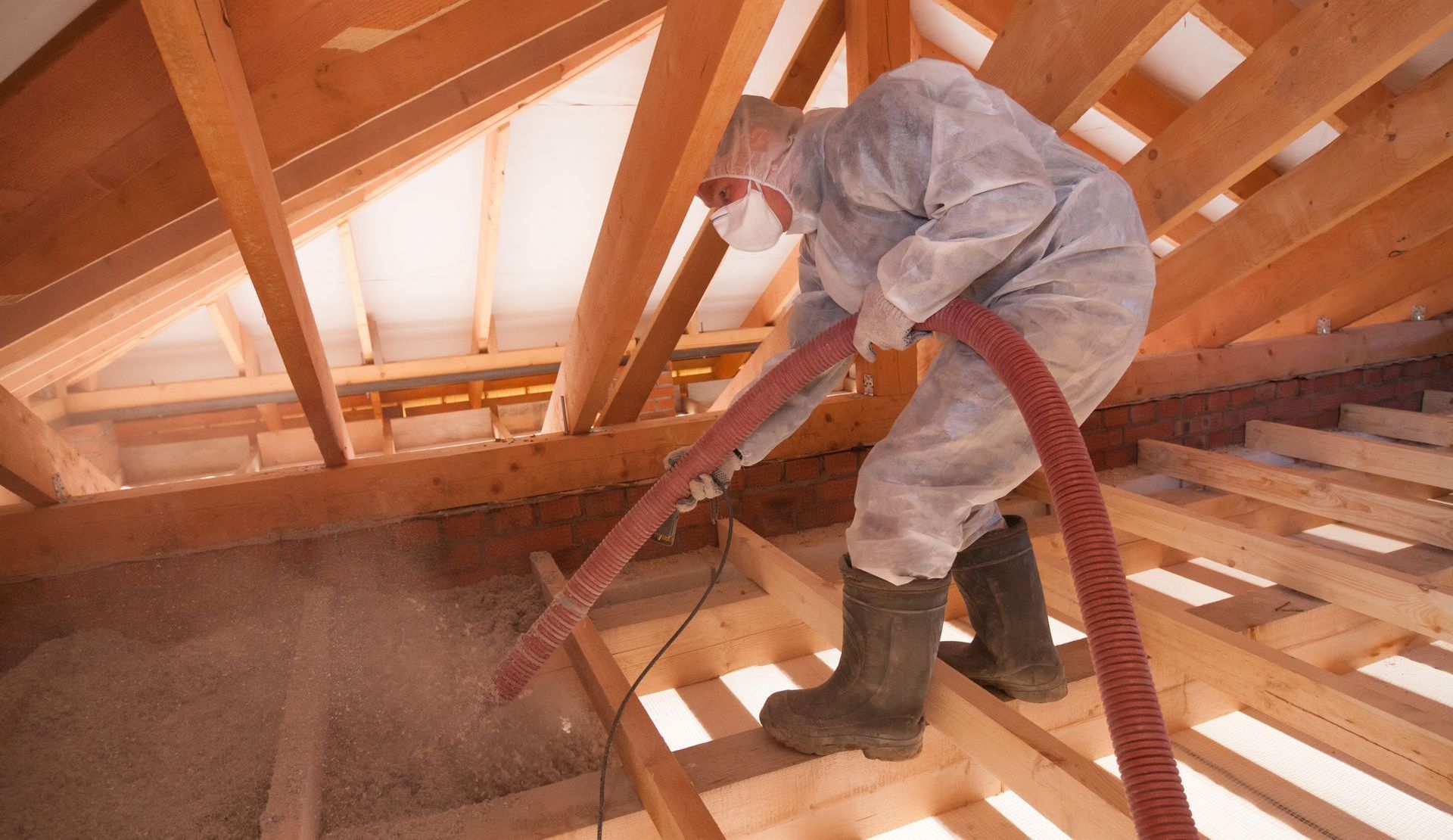 a man is blowing insulation into the attic of a house .