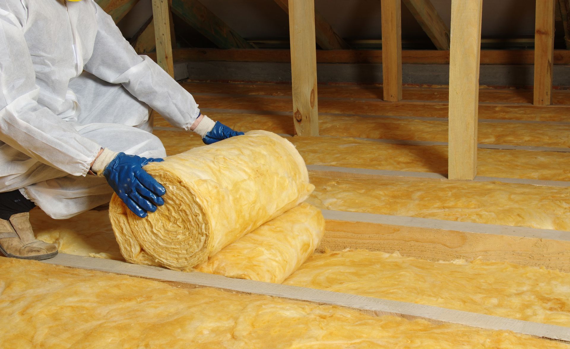 a person is rolling a roll of insulation on a wooden floor .